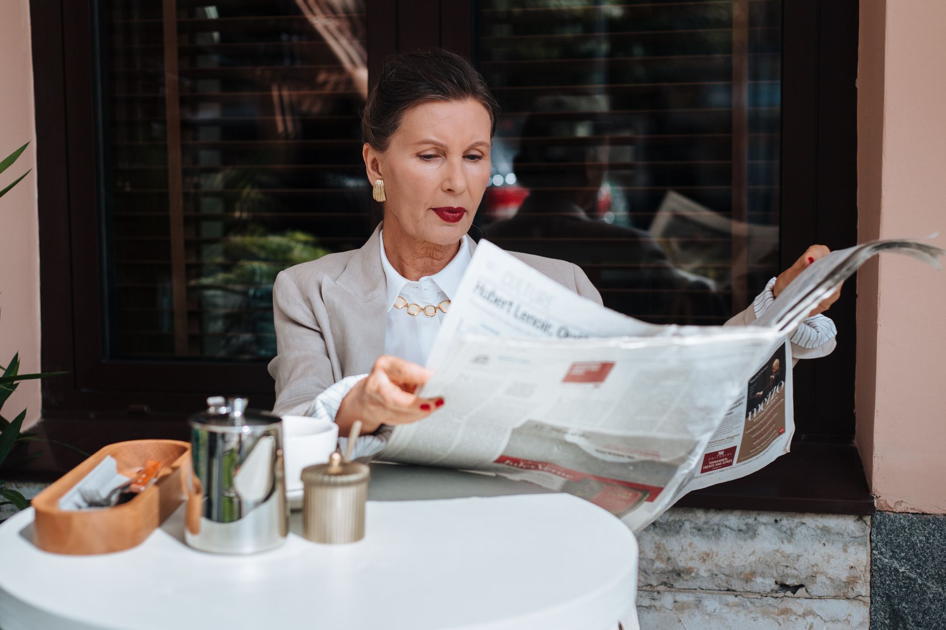 Sophisticated woman enjoying her morning newspaper at a cozy outdoor cafe. — Was macht Crazybuzzer Casino zur ersten Wahl?
