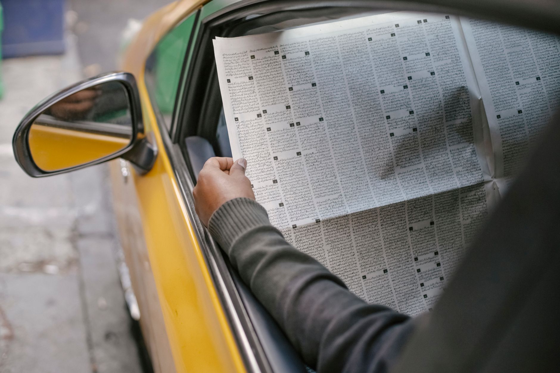 Crop unrecognizable person reading daily newspaper while sitting in car with opened window — Worauf achten bei der Registrier